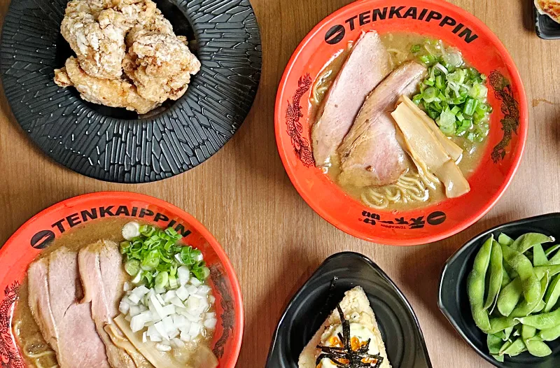 Tenkaippin ramen bowls, fried chicken, and side dishes on the table